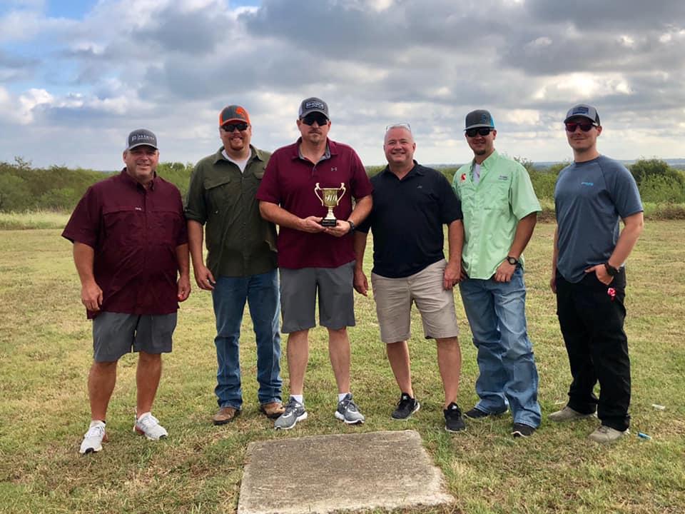 a group of skeet shooters pose with a trophy